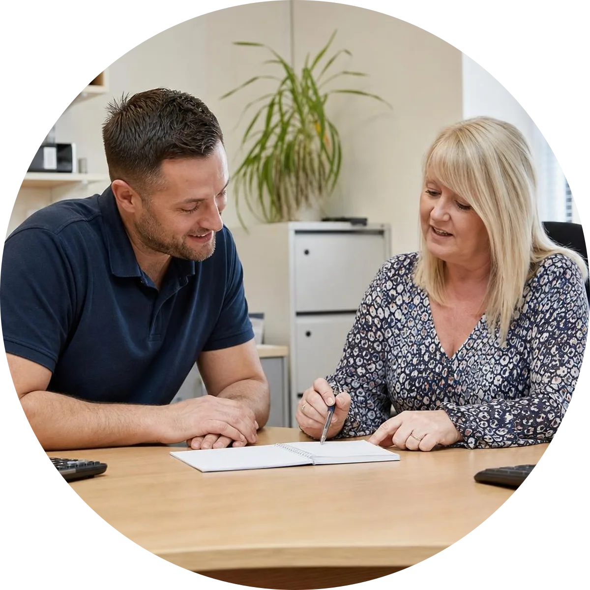 An employee and manager reviewing a training request with a notebook and calculator